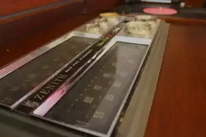 Close-up of original silver and gold control knobs and radio tuner dial on a restored mid-century Zenith stereo console.