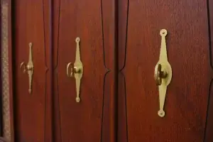 Close-up of a restored mid-century Zenith stereo console featuring rich walnut wood grain and iconic gold hourglass brass pulls.