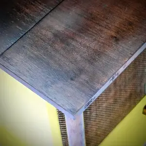 Corner of a wooden table or cabinet with a yellow base.