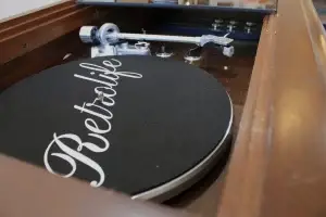 Close-up view of a modern Retrolife turntable with the smoked glass top open on a restored RCA Victor console.