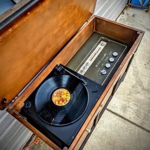 Vintage record player with a vinyl record playing, inside a wooden case.