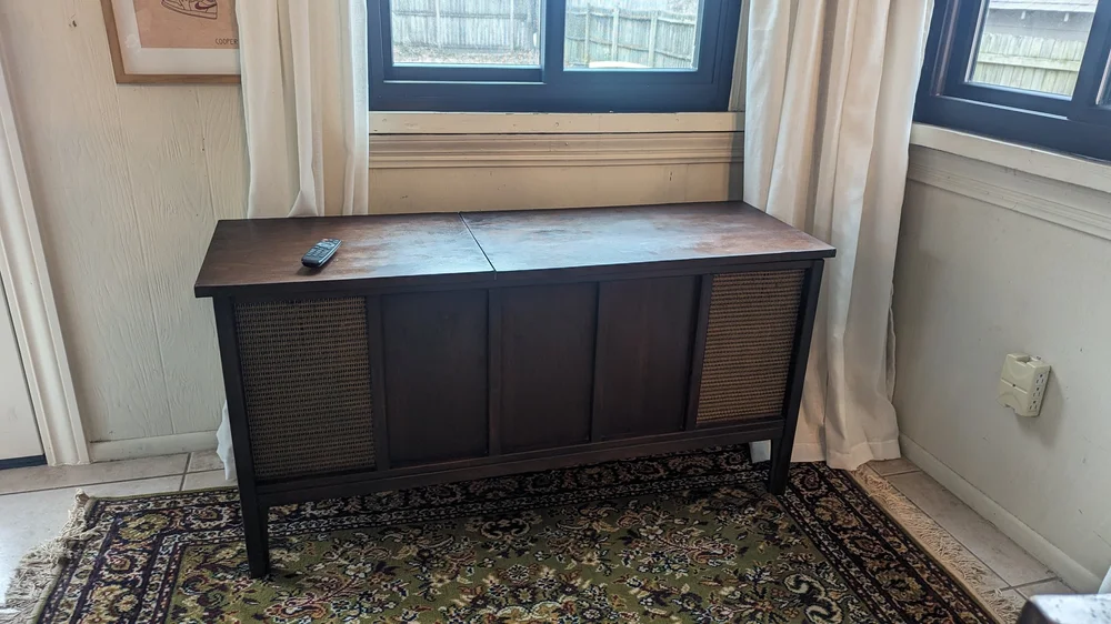 Dark wooden cabinet with wicker doors on a patterned rug.