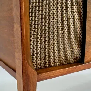Close-up of a wooden speaker with a woven grille.