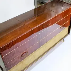 A vintage wooden dresser with three drawers and a wicker panel.