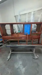 A mid-century Philco stereo console cabinet on a workshop table, showing the rich new wood stain being applied to the walnut grain.