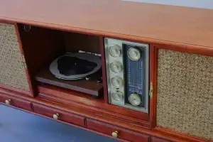 Interior view of a restored Philco stereo console with the sliding front panel open to reveal a modern turntable and a vintage radio tuner dial.