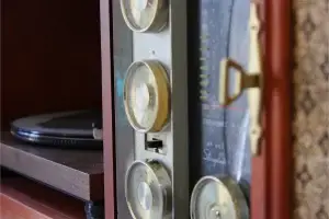 Close-up of the original gold radio tuner knobs and gold-toned sliding door pull on a refinished Philco mid-century stereo console.