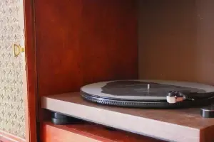 Close-up of a vinyl record spinning on a modern precision turntable installed inside a refinished Philco mid-century stereo console.
