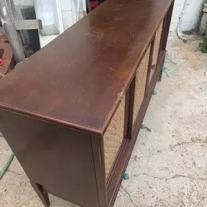 A vintage Philco mid-century stereo console in its original, unrestored condition sitting outdoors, showing dusty wood surfaces and the original internal components.