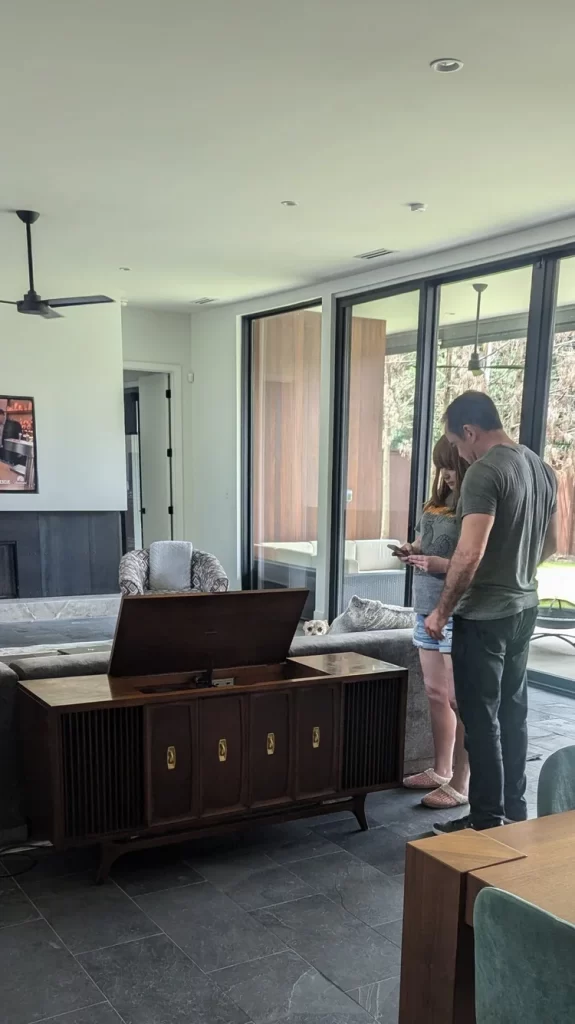 Couple standing in a modern living room with large windows.