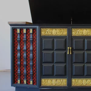 Ornate black cabinet with gold accents and red glass.