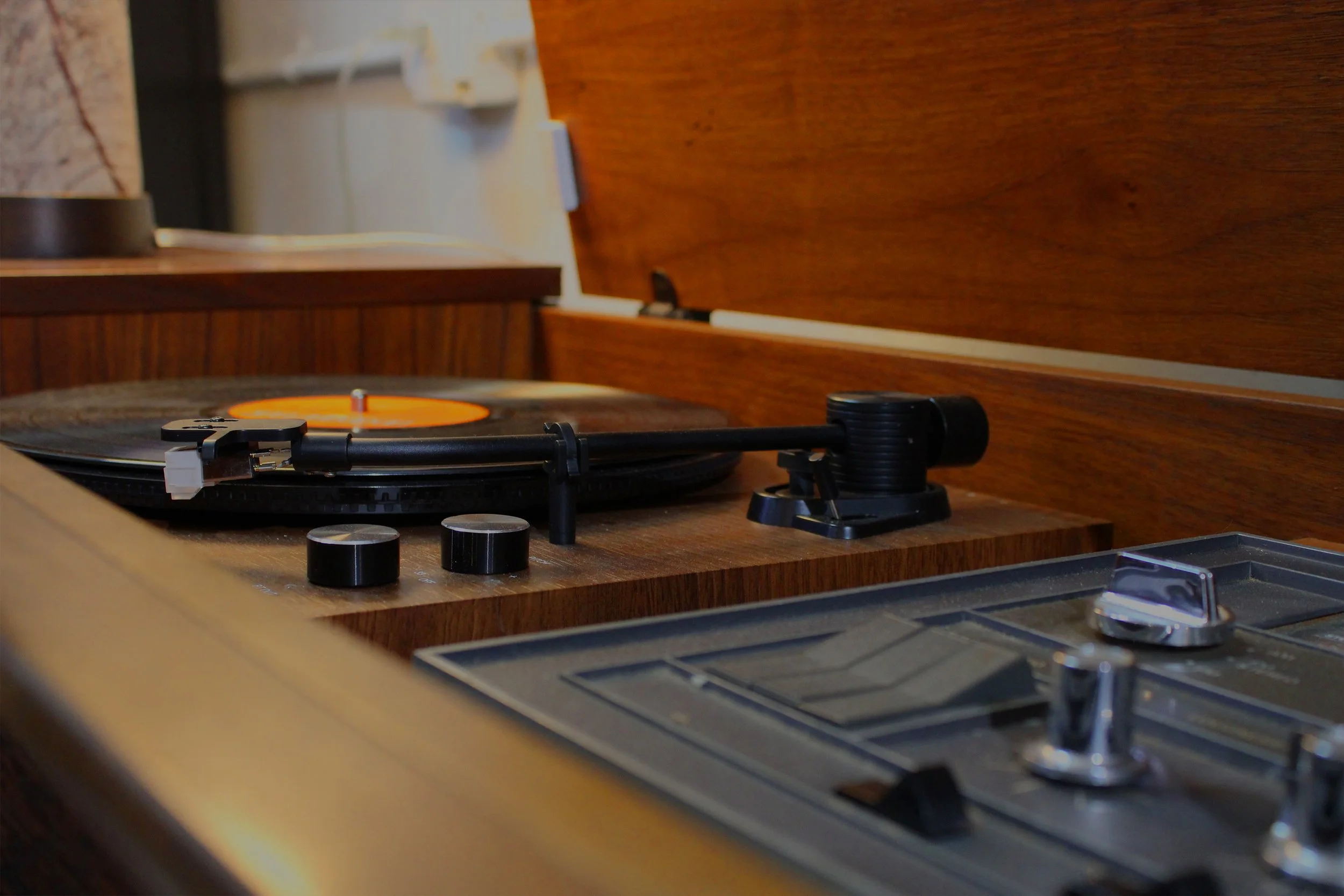 Record player on a wooden console, playing a vinyl.