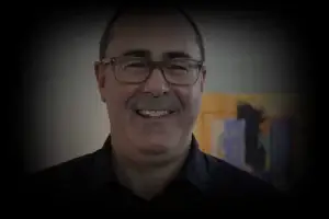 Mike, a happy client, smiling in front of a bookshelf.