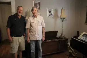 Happy Steiner Audio client standing in a room with a piano and saxophone.