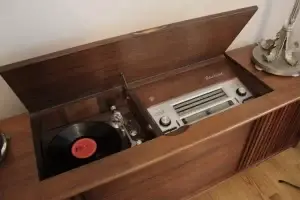 Vintage record player with a vinyl record playing on a wooden cabinet.
